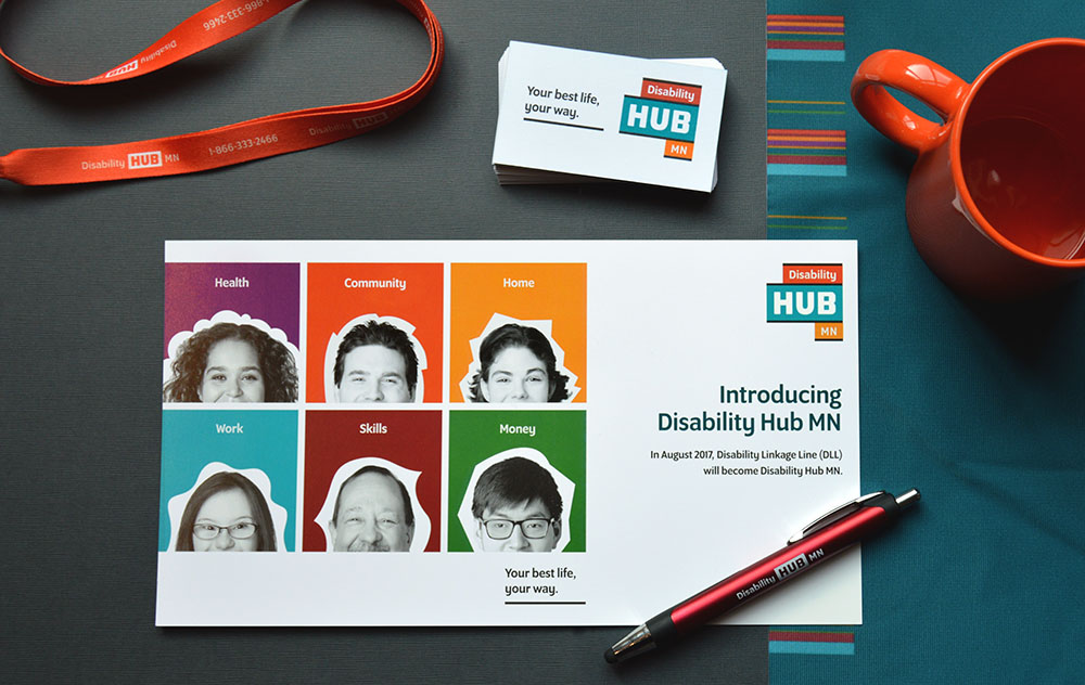 Disability Hub MN promotional materials—a lanyard, business cards, postcard and pen on a desk