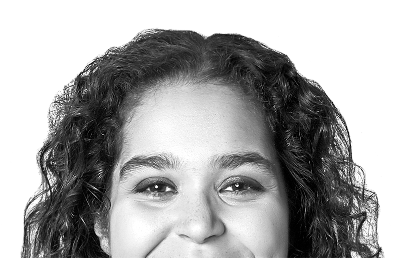 A person with long, curly hair is smiling at the camera. We can see their eyes and nose, but the photo is cropped above their mouth.